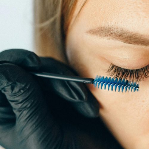 pexels-photo-5128267-5128267 A professional applying eyelash extensions using a blue applicator brush for a refined look.